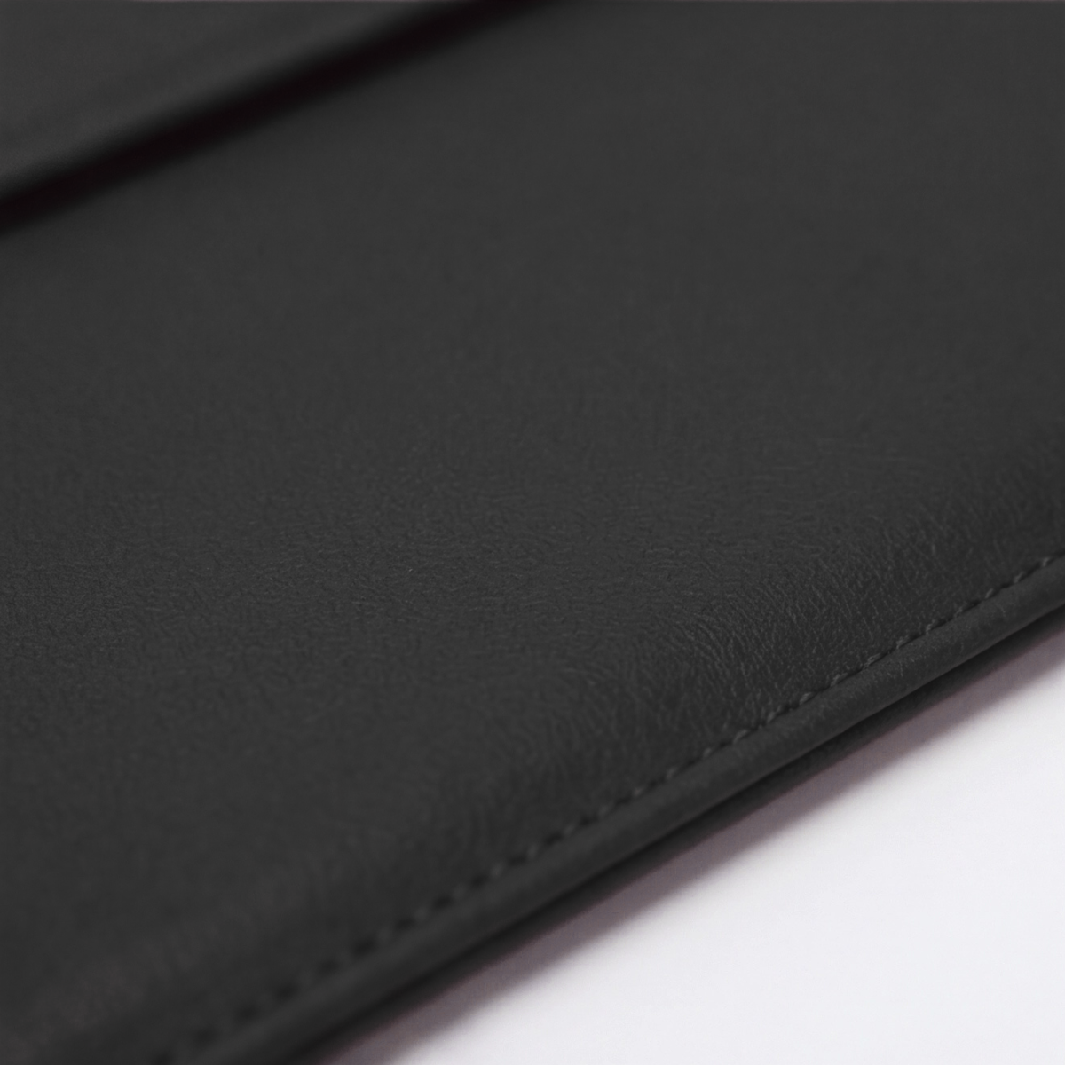 Black laptop sleeve fabric close-up with visible seam and textured finish