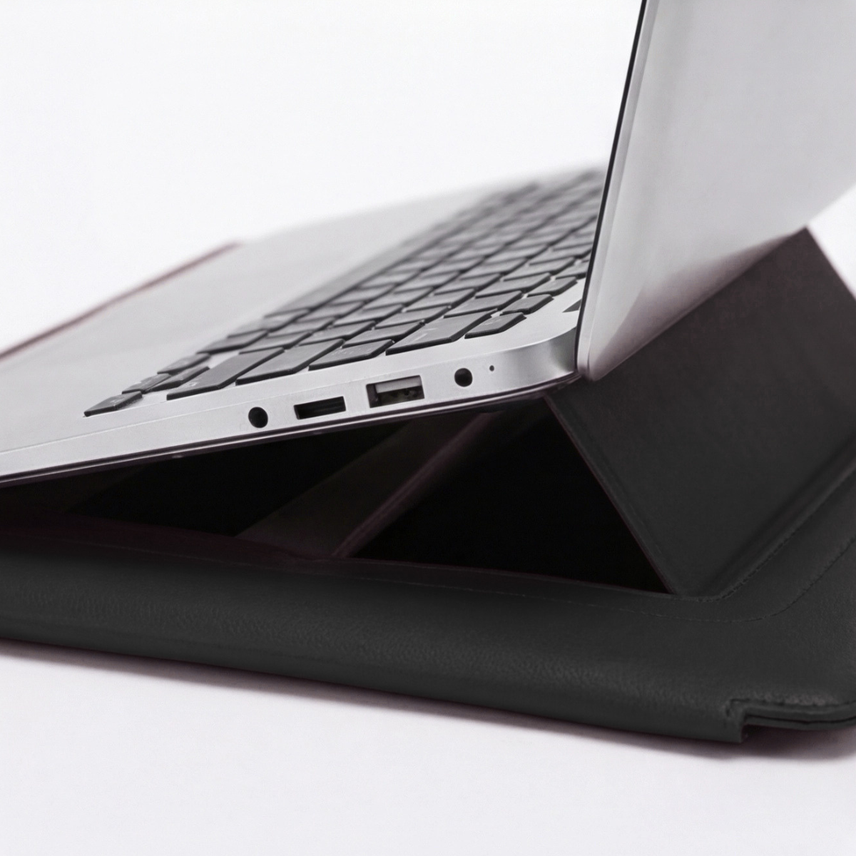 Black laptop sleeve with raised stand, laptop ports visible at the edge