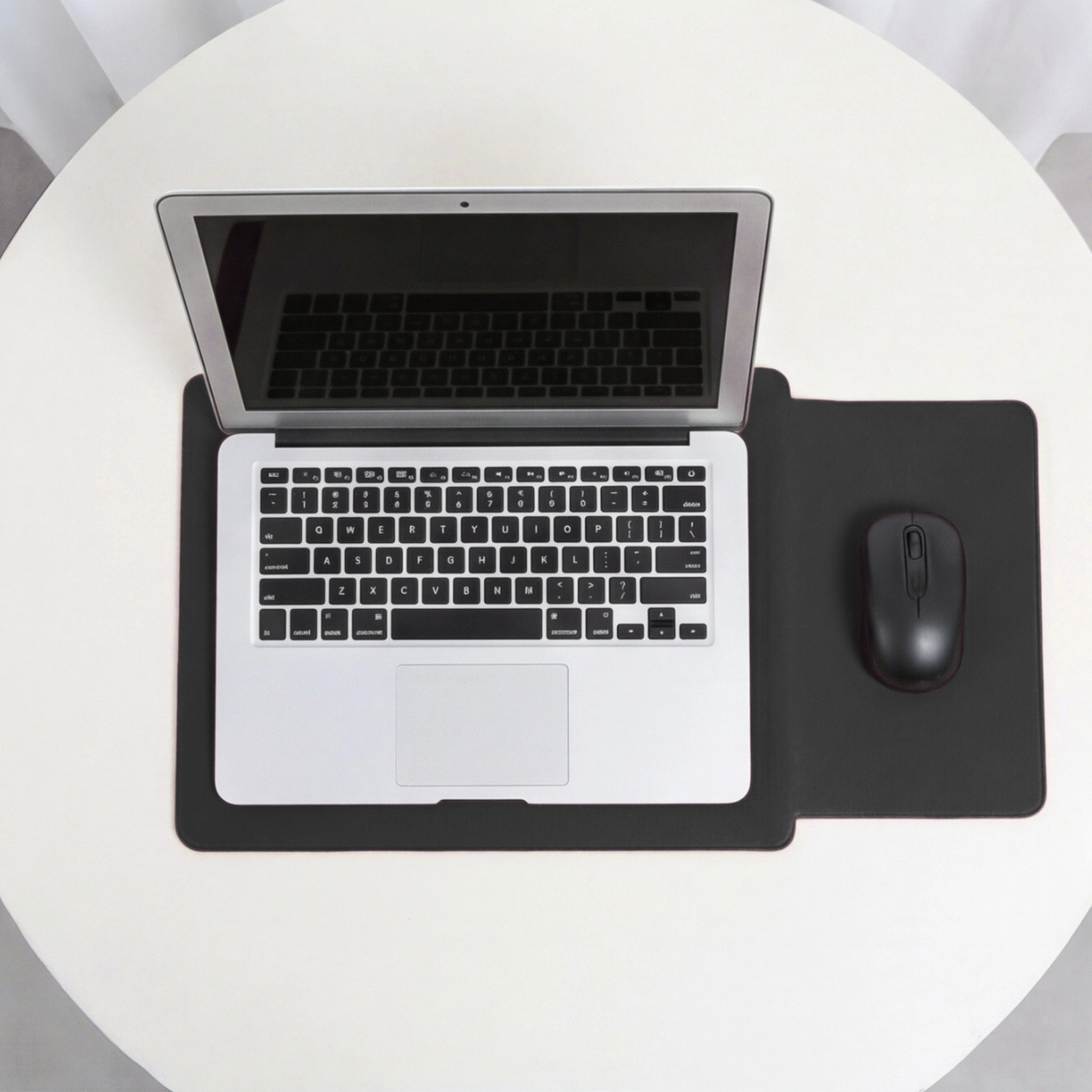 Black laptop sleeve on desk with laptop and integrated mouse pad