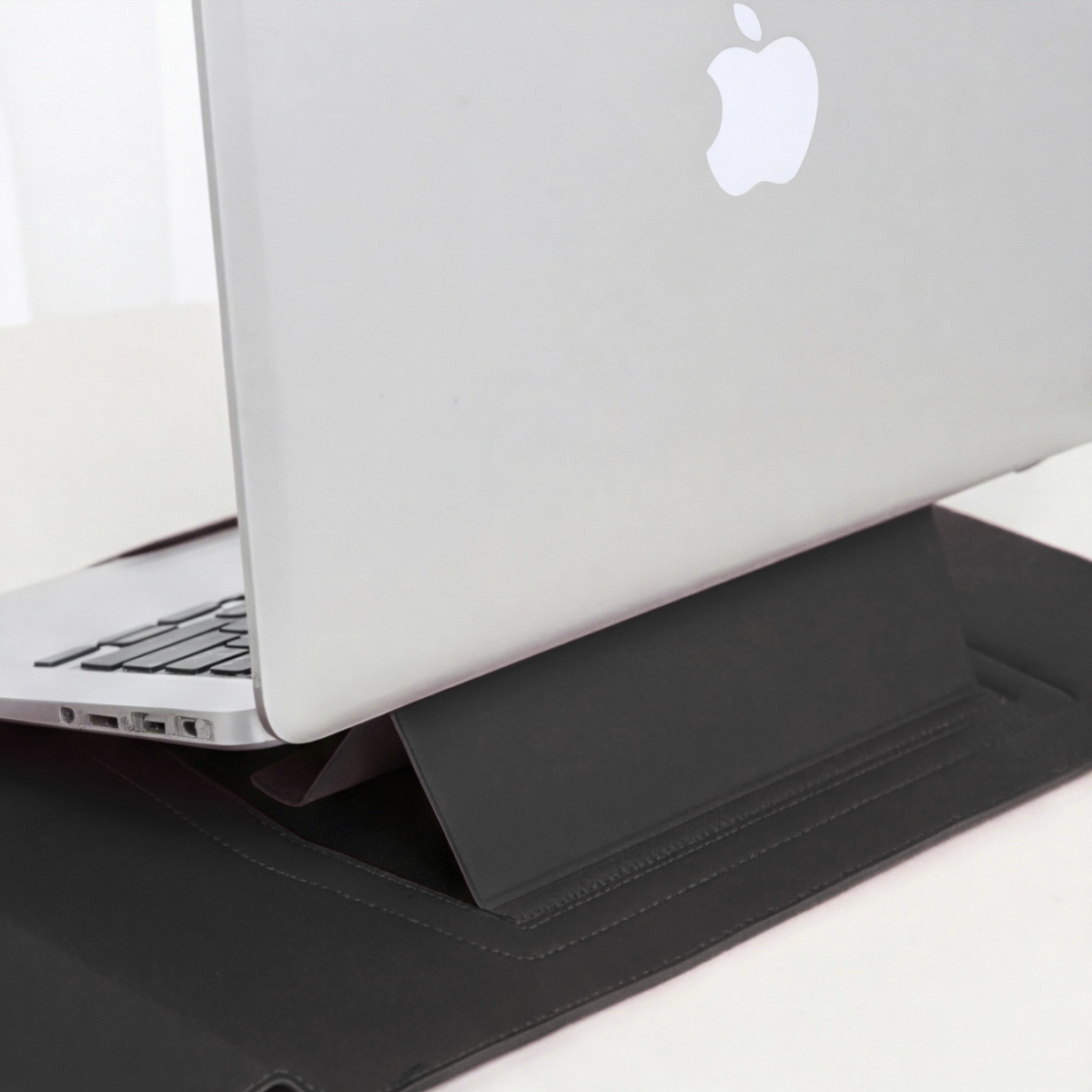 Black laptop sleeve with built-in stand supporting laptop, side view